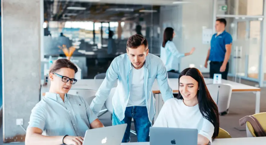 Equipo colabora en un proyecto, usando laptops y aplicaciones informáticas para gestionar la cuenta contable.