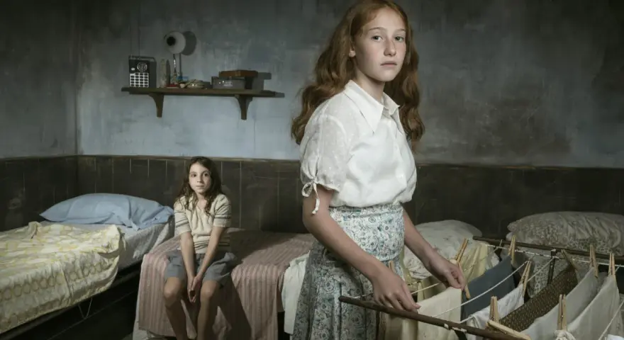Due bambine in una stanza spartana, una stende il bucato, l'altra siede sul letto. Ricorda l'arminuta storia vera.