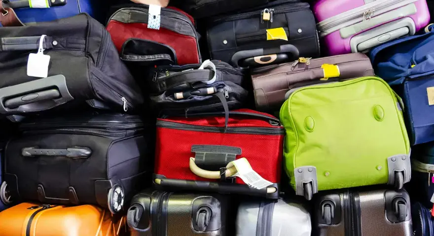 A large pile of various suitcases and bags in different colors, stacked high.