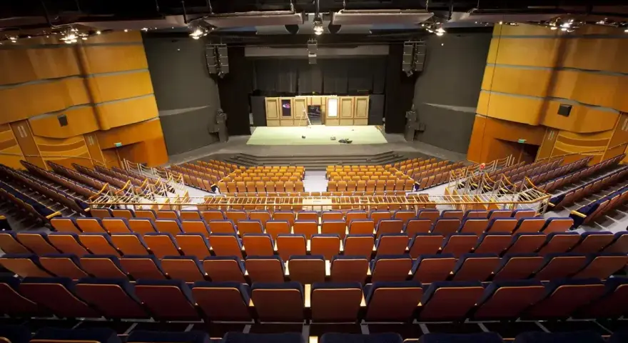 Pusta widownia Teatru Muzycznego im. Danuty Baduszkowej. Pomarańczowe fotele czekają na widzów, scena gotowa na spektakl.