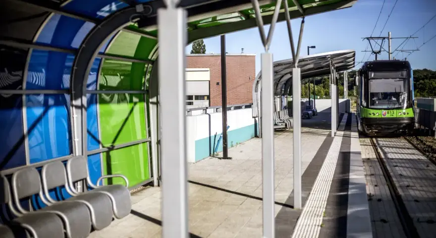 Nowoczesny przystanek tramwajowy w Szczecinie. Zielony tramwaj czeka na pasażerów. Jak dojechać do centrum?