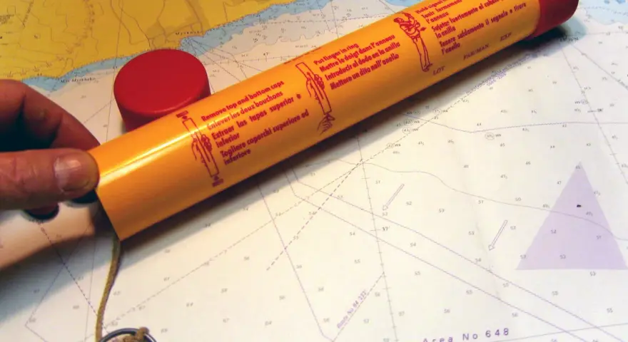 Seenot-Leuchtrakete mit roter Kappe und Anleitung auf einer Seekarte.
