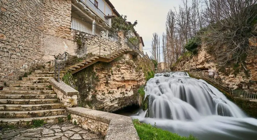 Escaleras de piedra y un caserío se funden con la cascada en la Alcarria Alta.