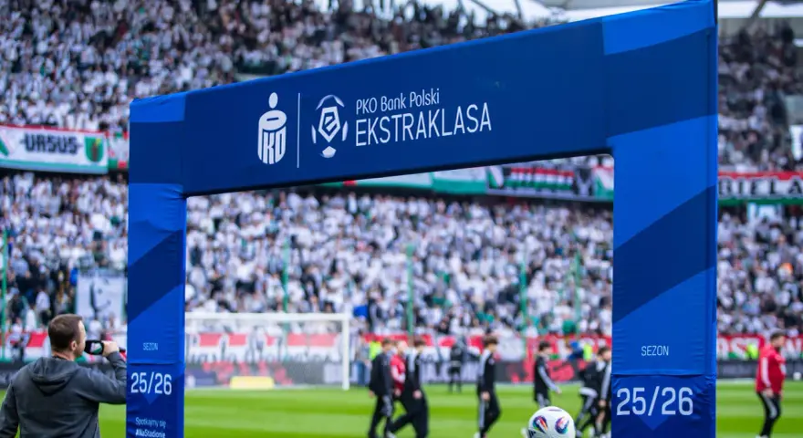 Brama z logo PKO Bank Polski Ekstraklasa na tle stadionu i kibiców. Sezon 25/26.