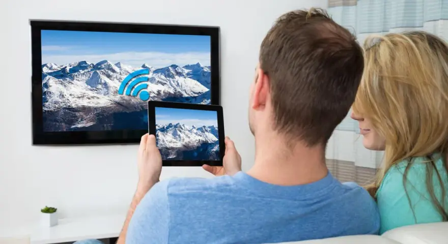 Ein Paar verbindet sein iPad mit dem Fernseher, um die Berglandschaft auf dem großen Bildschirm zu genießen.