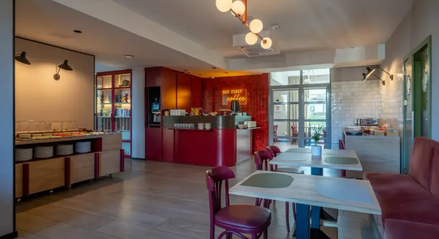 Nowe, stylowe wnętrze z bufetem śniadaniowym i neonem "But first coffee". Idealne miejsce na poranną kawę, zgodnie z licznymi hotel Antares opinie.