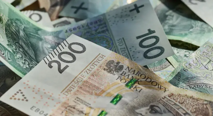 Złotówki, w tym banknot 200 zł, tworzą stos. Marzenia o wakacjach w 2026 roku? Trzynastka pomoże!