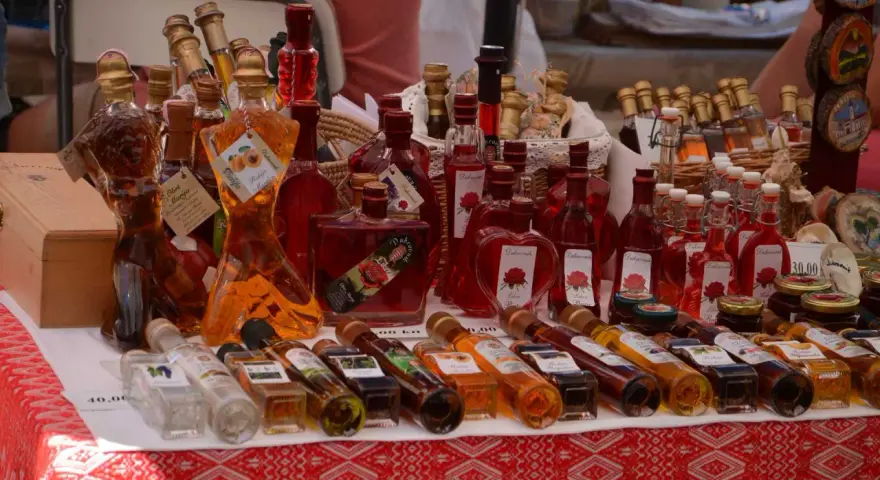 Różnorodne butelki z rakiją, w tym te o fantazyjnych kształtach, prezentują bogactwo smaków. Co to rakija? To tradycyjny alkohol, często owocowy.