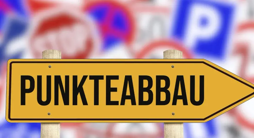 Gelbes Schild mit der Aufschrift "PUNKTEABBAU" weist den Weg. Informieren Sie sich über die fahreignungsseminar kosten, um Punkte abzubauen.