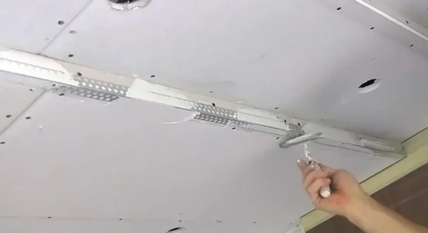 Hand spachtelt Rigipsdecke, um eine glatte Oberfläche für den Innenausbau zu schaffen.