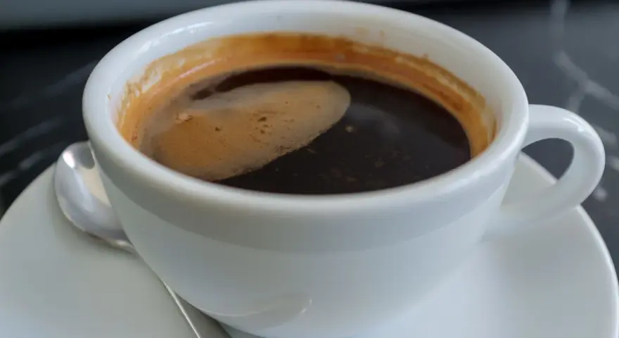 Aromatic coffee in a white cup, a moment to ponder: czy kawa jest zdrowa? The rich crema hints at a complex flavor.