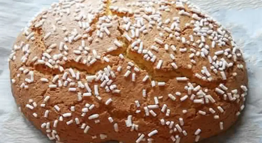 Ciambella romagnola artusi, soffice e dorata, cosparsa di zuccherini bianchi. Un dolce che sa di casa e tradizione.