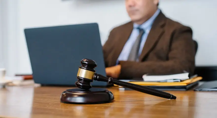 Sądowy młotek na biurku, prawnik pracuje przy laptopie. Dyskrecja w ujawnieniu informacji o zadłużeniu osobom trzecim.