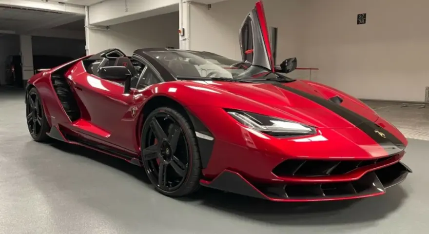 Czerwony kabriolet Lamborghini Centenario z otwartymi drzwiami typu nożycowego.