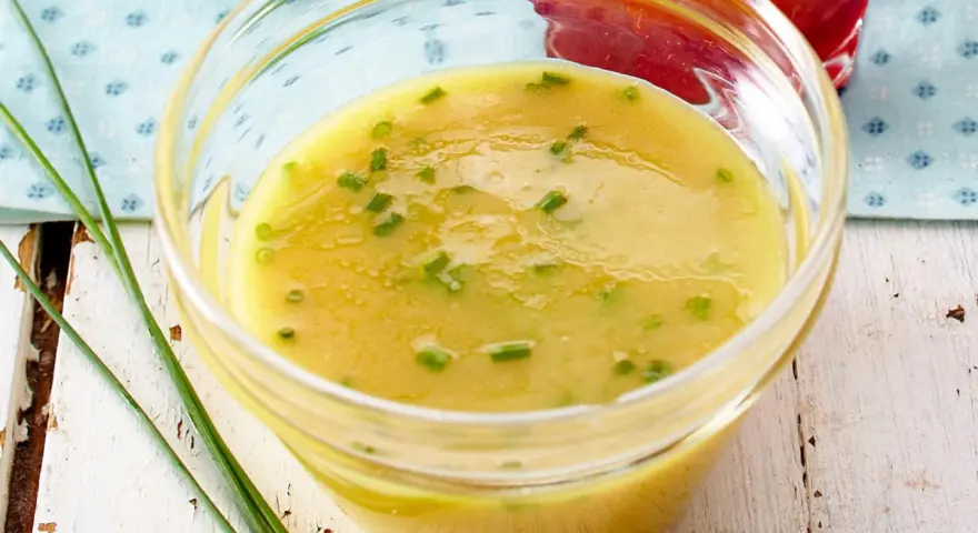 Ein Glas mit cremigem honig senf dressing, garniert mit Schnittlauch. Perfekt für einen frischen Salat.