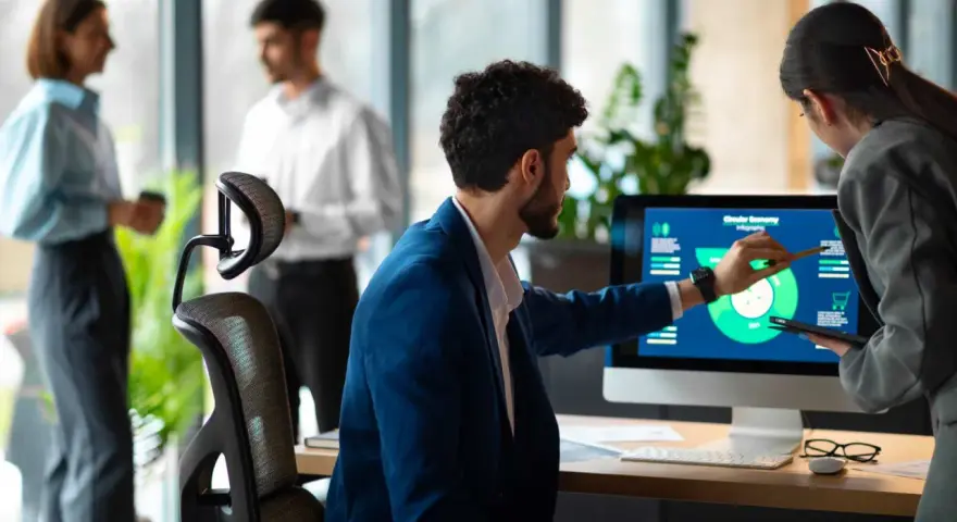 Uomini e donne discutono di grafici su un monitor, esplorando nuove opportunità di lavori del futuro senza laurea.