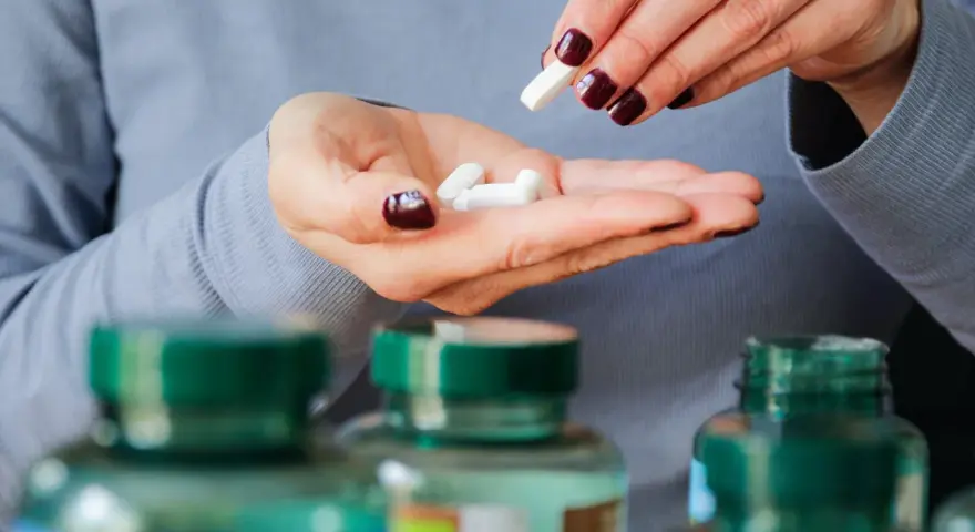 Frau nimmt Pillen, darunter 5-HTP, aus ihrer Hand.
