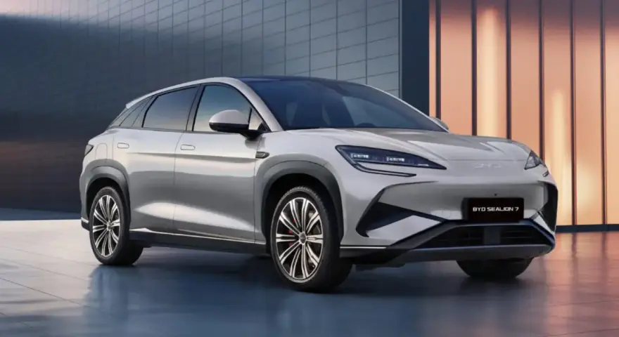 Srebrny SUV BYD Sealion 7 z nowoczesnym designem, zaparkowany przed budynkiem.