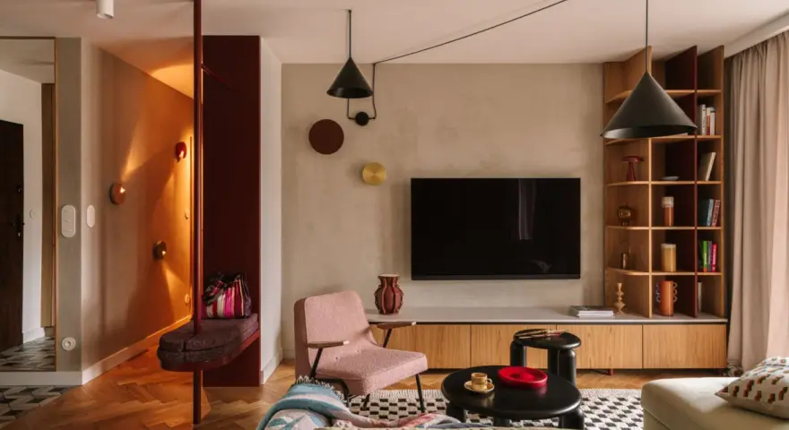 Nowoczesny salon z elementami boho. Wygodna kanapa, różowy fotel, czarne stoliki i regał. W przedpokoju ławka i lustro. Idealne miejsce na relaks po całym dniu. Ten **kosztorys remontu** był wart każdej złotówki.
