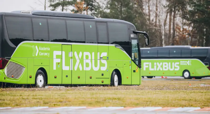 Zielony autobus Flixbus z napisem "Akademia Kierowcy" stoi na trawie. Czyżby kolejne flixbus opóźnienia?