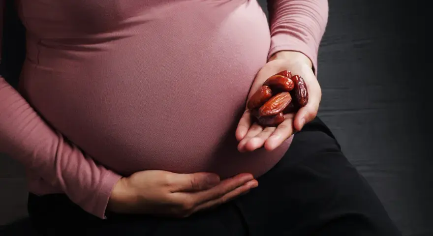 Kobieta w ciąży trzyma w dłoni garść daktyli. To naturalny sposób na wsparcie organizmu w tym wyjątkowym czasie.