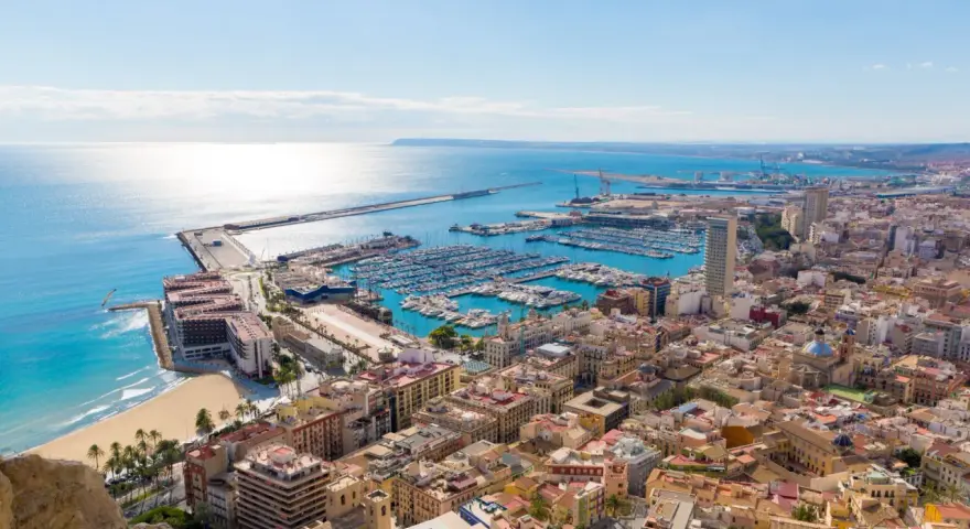 Widok na port jachtowy i plażę w słoneczny dzień. Tak właśnie wygląda Alicante, gdzie jest to piękne miasto.