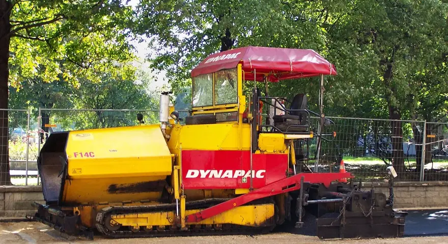 Żółto-czerwony rozściełacz do kruszywa Dynapac F14C na placu budowy.