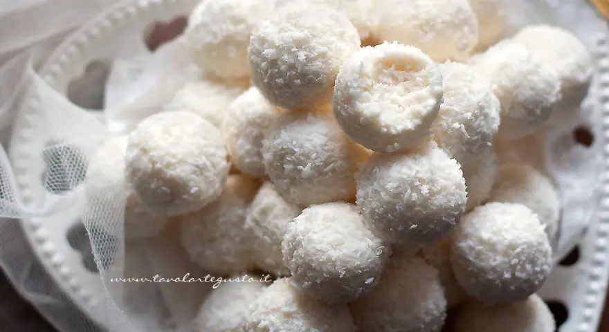 Dolci palline di cocco, morbide e profumate, adagiate su un piatto decorato con un velo di tulle.