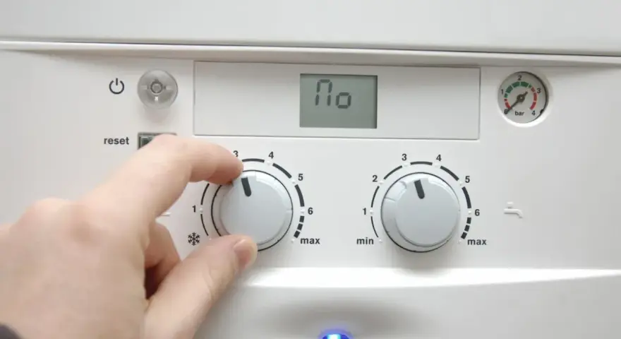 Dłoń reguluje pokrętłem pieca, przygotowując dom na nadchodzący sezon grzewczy. Na wyświetlaczu widnieje "110".