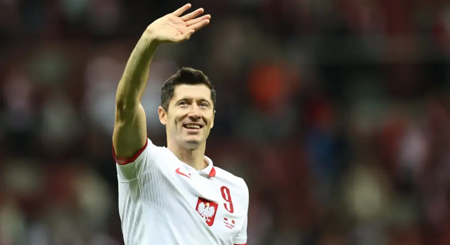 Robert Lewandowski w koszulce reprezentacji Polski z numerem 9, macha do kibiców.