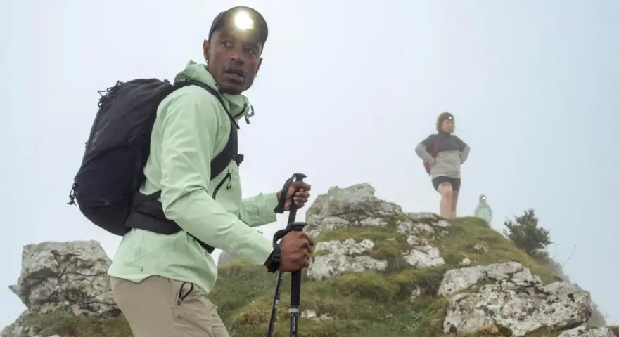 Randonneur ajustant son réglage bâton de marche, prêt à affronter la brume avec sa lampe frontale.