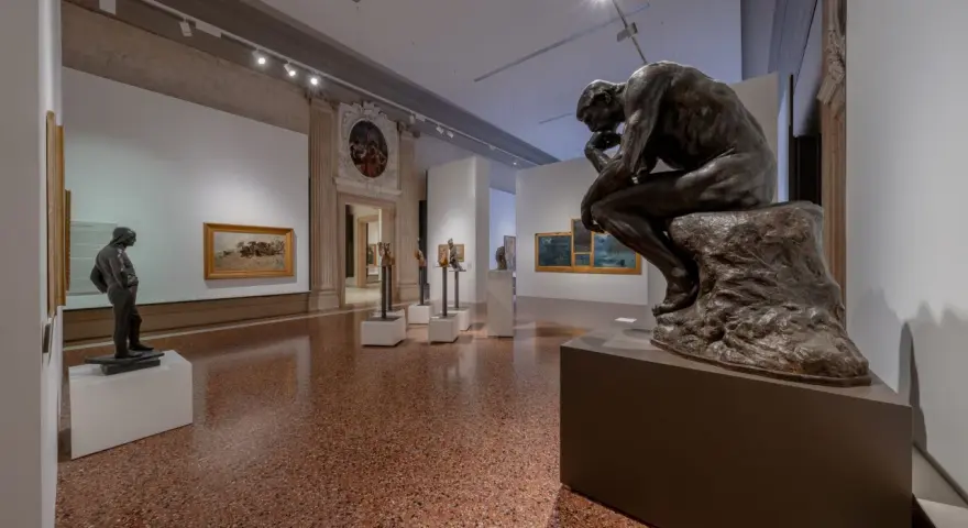 Il Pensatore di Rodin domina la sala del museo Ca' Pesaro, circondato da altre sculture e dipinti.