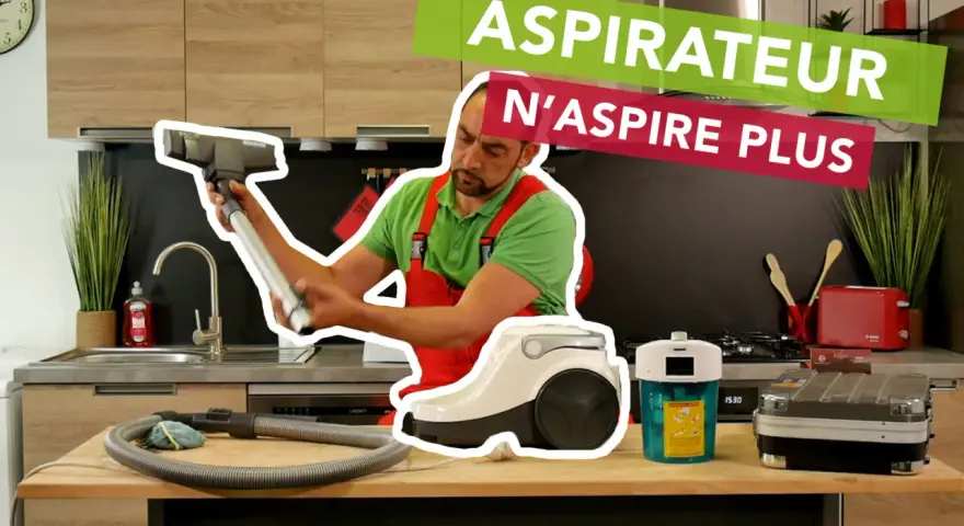 Un homme en salopette rouge examine un aspirateur, perplexe. Le texte superposé indique "ASPIRATEUR N'ASPIRE PLUS".