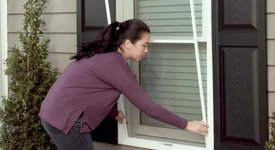 Woman demonstrates how to replace screen door mesh on a window.