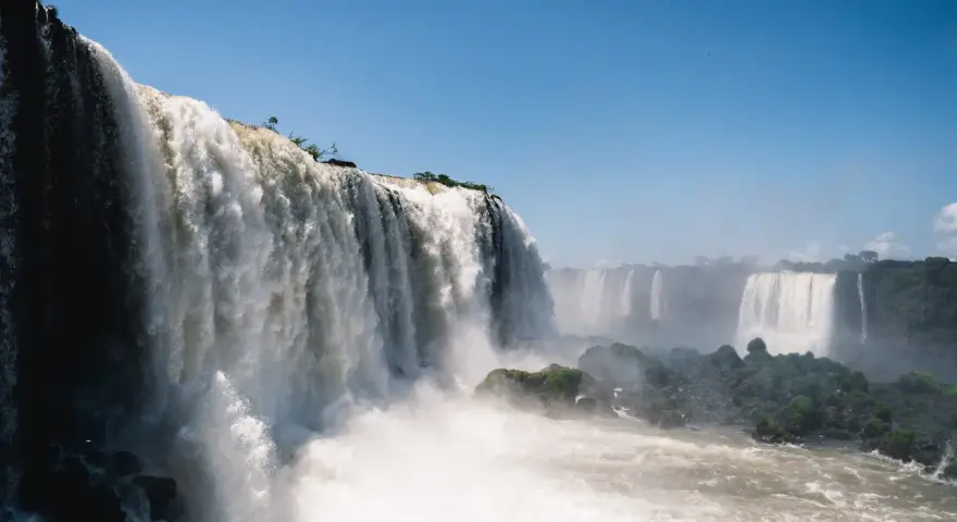 Potężne wodospady Iguazú w Argentynie, kaskady wody spadające z klifów, otoczone zielenią i spowite mgiełką.
