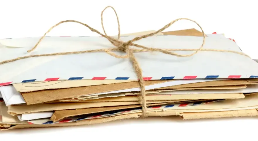Stos listów w kopertach rozmiar C3, związany sznurkiem. Widać różne rodzaje papieru i ozdobne paski.