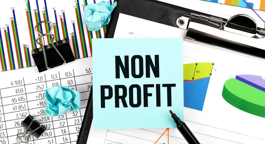 Analyzing financial reports for nonprofits. The image shows charts, graphs, and a sticky note with "NON PROFIT" written on it.