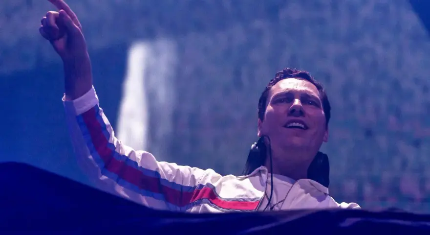 DJ Tiësto w Polsce, z palcem uniesionym w górę, wita publiczność.