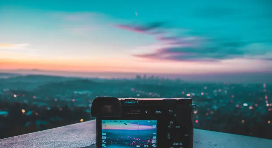Aparat fotograficzny na tle miejskiego krajobrazu o zachodzie słońca. Piękne, kolorowe światło maluje niebo.