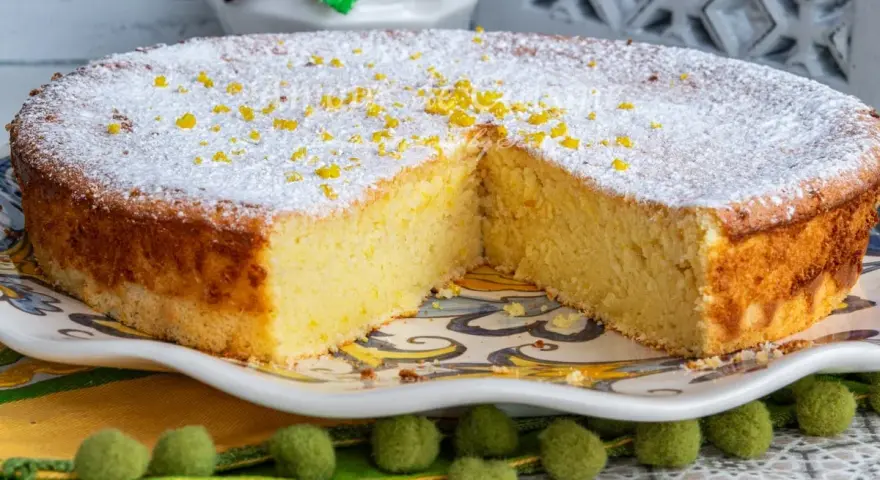 Un moelleux au citron, saupoudré de sucre glace et de zestes, attend d'être dégusté. Sa texture aérienne promet un délice.