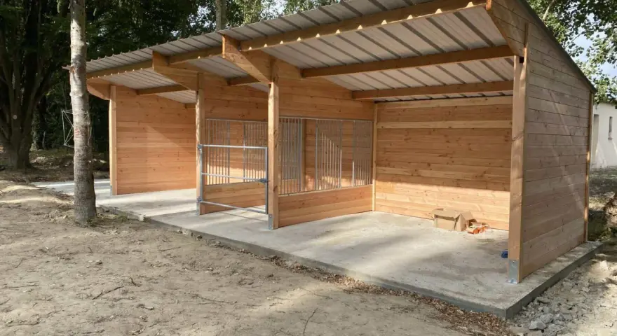 Nouveau box chevaux fait maison en bois, avec toit métallique et barrières en métal. Prêt à accueillir vos compagnons.