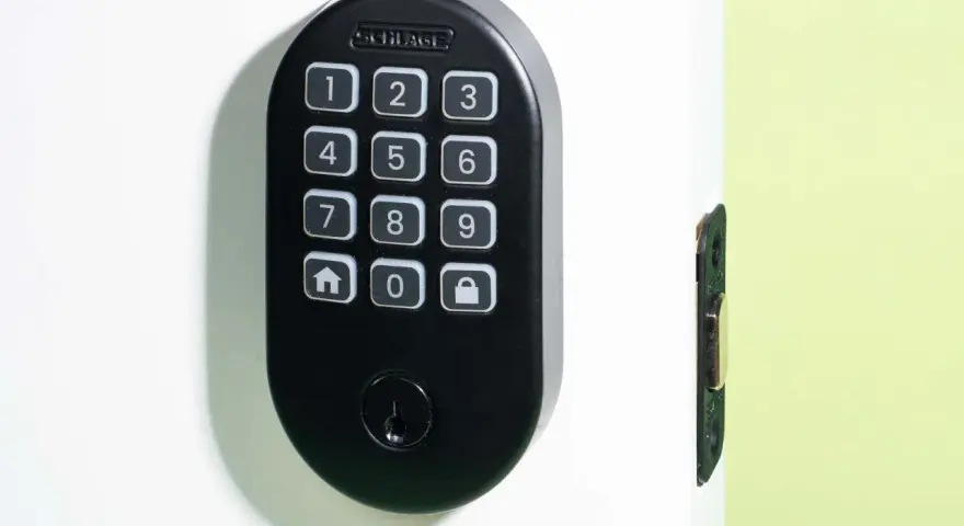 Black Schlage keypad lock on a white door, showing numbers and icons. Learn how to change door lock code for enhanced security.