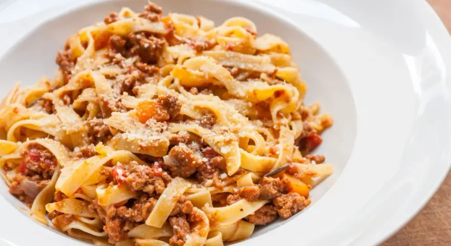 Tagliatelle z bogatym, mięsnym sosem bolońskim, posypane parmezanem. Pyszne danie, które zadowoli każdego miłośnika włoskiej kuchni.
