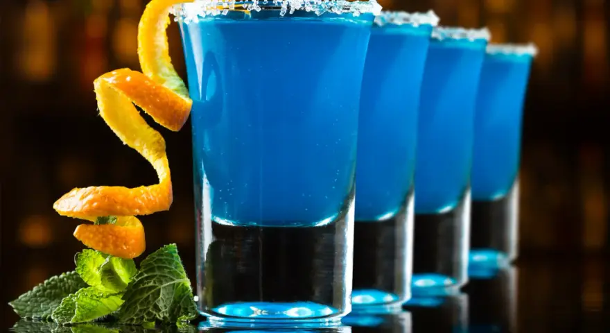 Niebieskie shoty Kamikaze, z pomarańczową skórką i miętą. Idealne, gdy nie masz blue curacao.