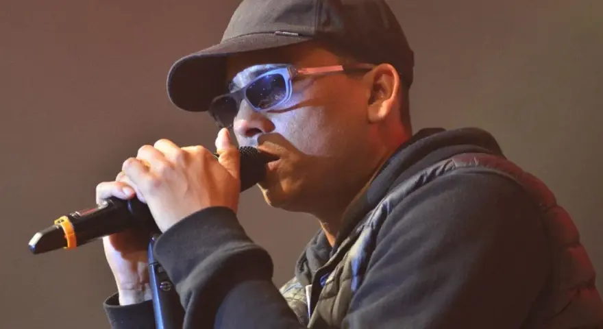Mann mit Kappe und Sonnenbrille singt ins Mikrofon. Ein starker musik comeback Moment.