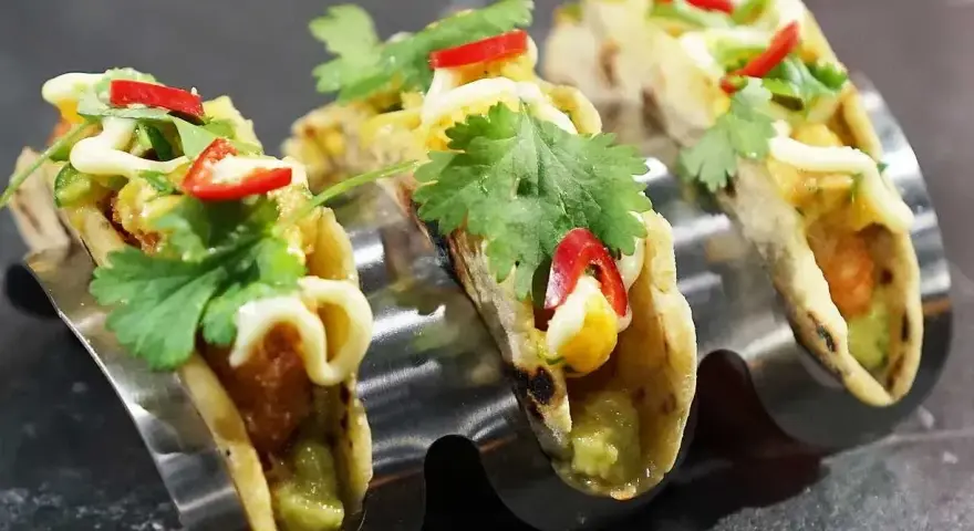 Tre läckra asiatiska tacos med koriander, chili och majs i en taco-hållare.