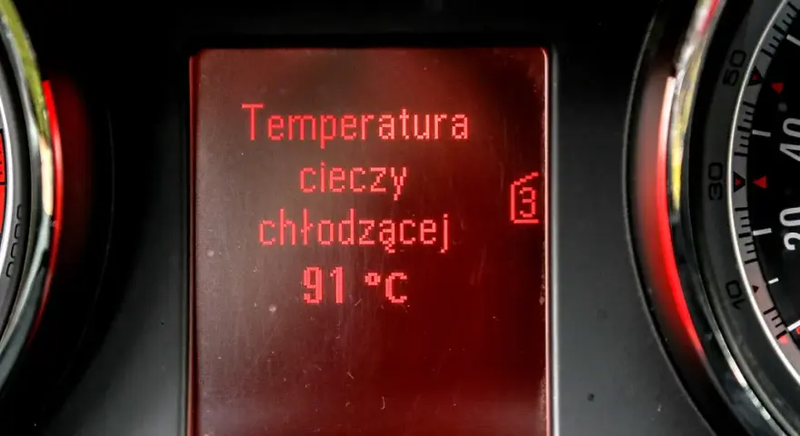 Wyświetlacz pokazuje temperaturę płynu chłodniczego: 91°C. Obok widać fragmenty wskaźników.