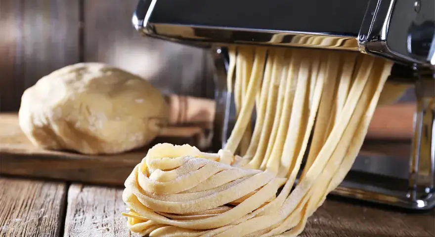 Maszyna do makaronu tworzy świeże tagliatelle z ciasta. Idealny sposób, jak zrobić makaron w domu.