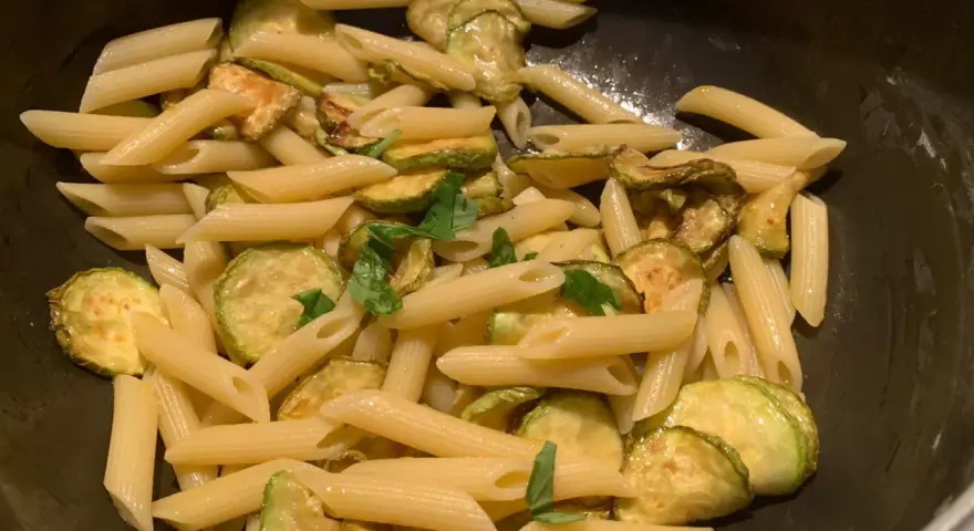 Penne con zucchine saltate e basilico fresco, un classico piatto di pasta e zucchine alla siciliana, pronto per essere gustato.