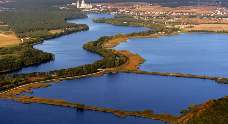 Widok z lotu ptaka na jezioro z wyspami, lasami i zabudowaniami w tle.
